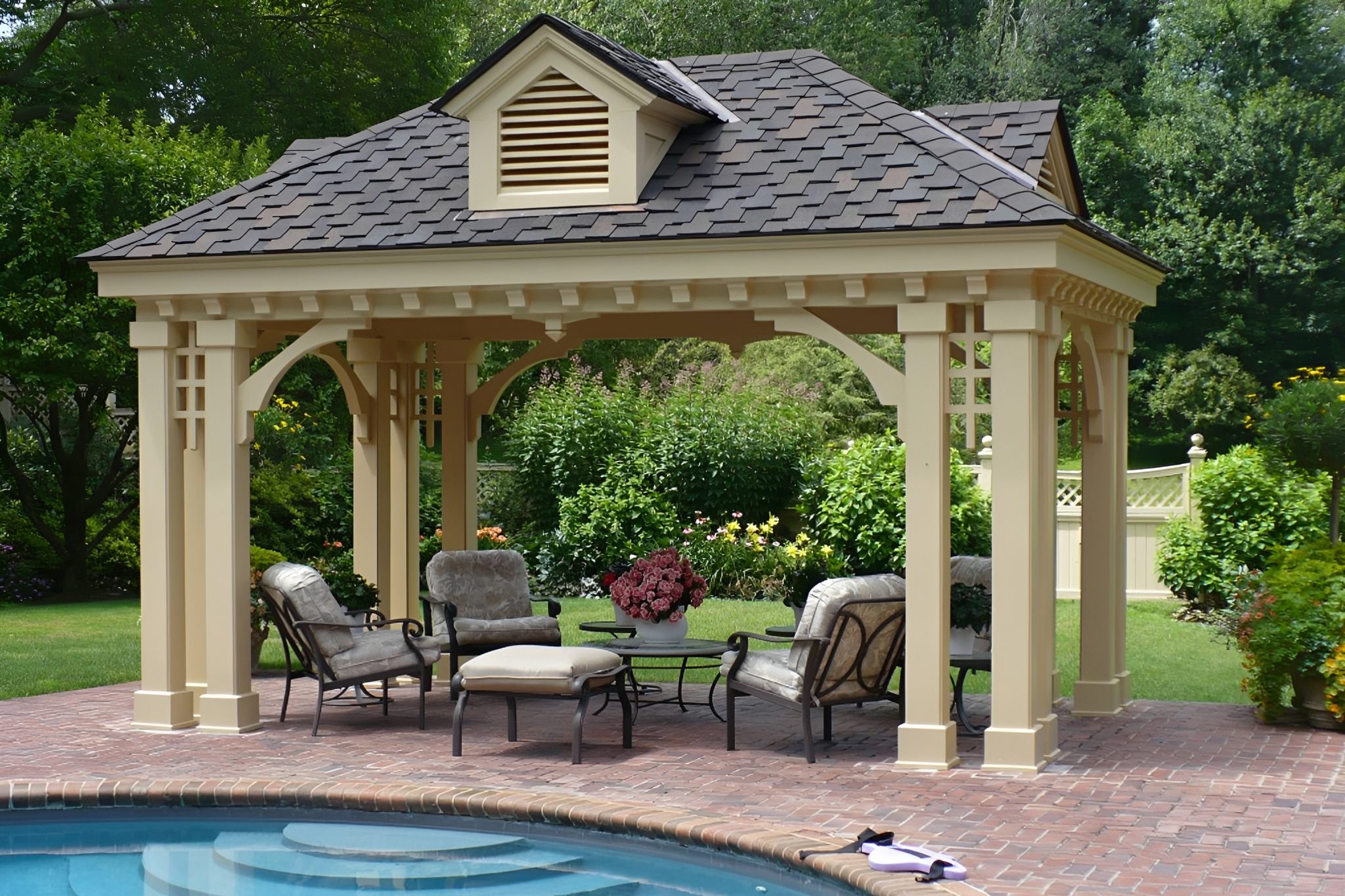 Garden gazebo with chairs by a pool.